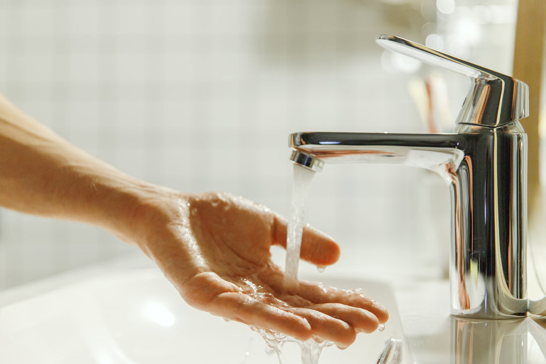Hand under running water from a bathroom faucet