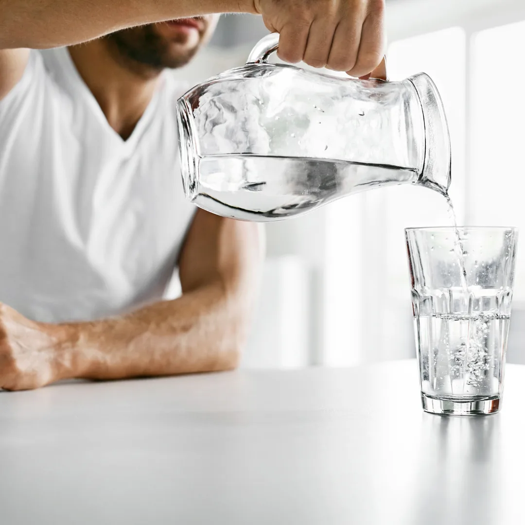 man pouring clean and filtered water into a clear glass