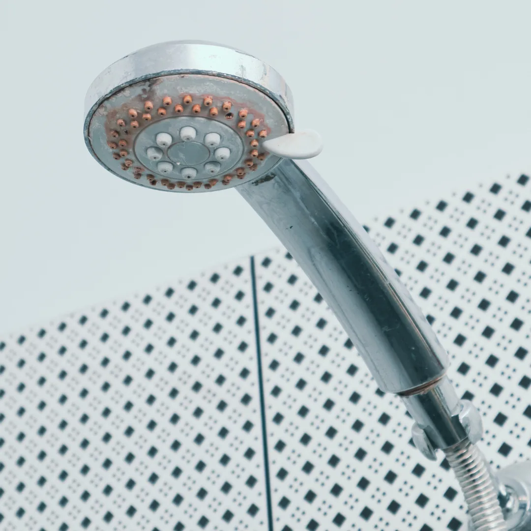 shower head with hard water damage and red stains