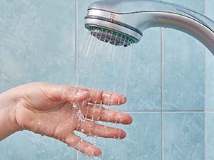 A hand being held out under a stream of water from a showerhead.