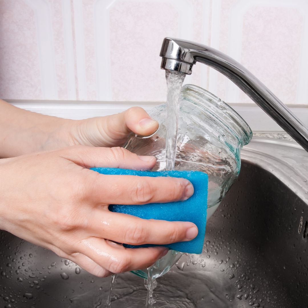 person washing glass jar in kitchen sink