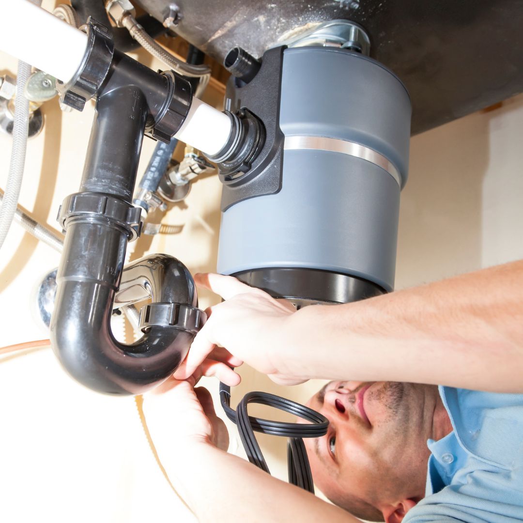 person repairing garbage disposal under sink