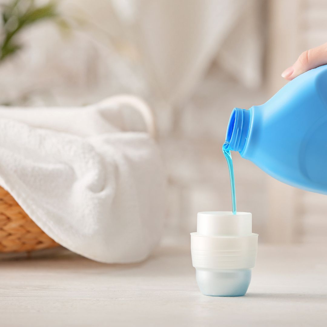 person pouring liquid laundry detergent into the cap of the detergent container