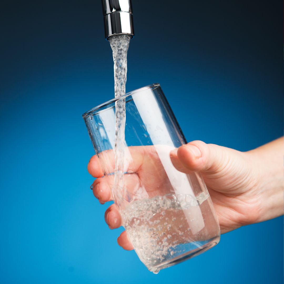 person holding glass under faucet pouring water