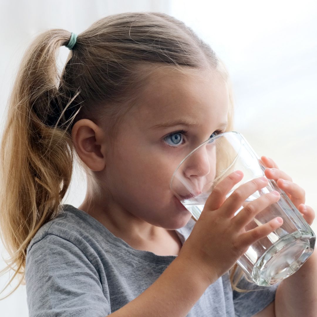 child drinking water out of glass