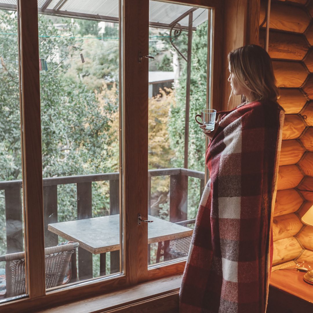 woman holding water looking out of window