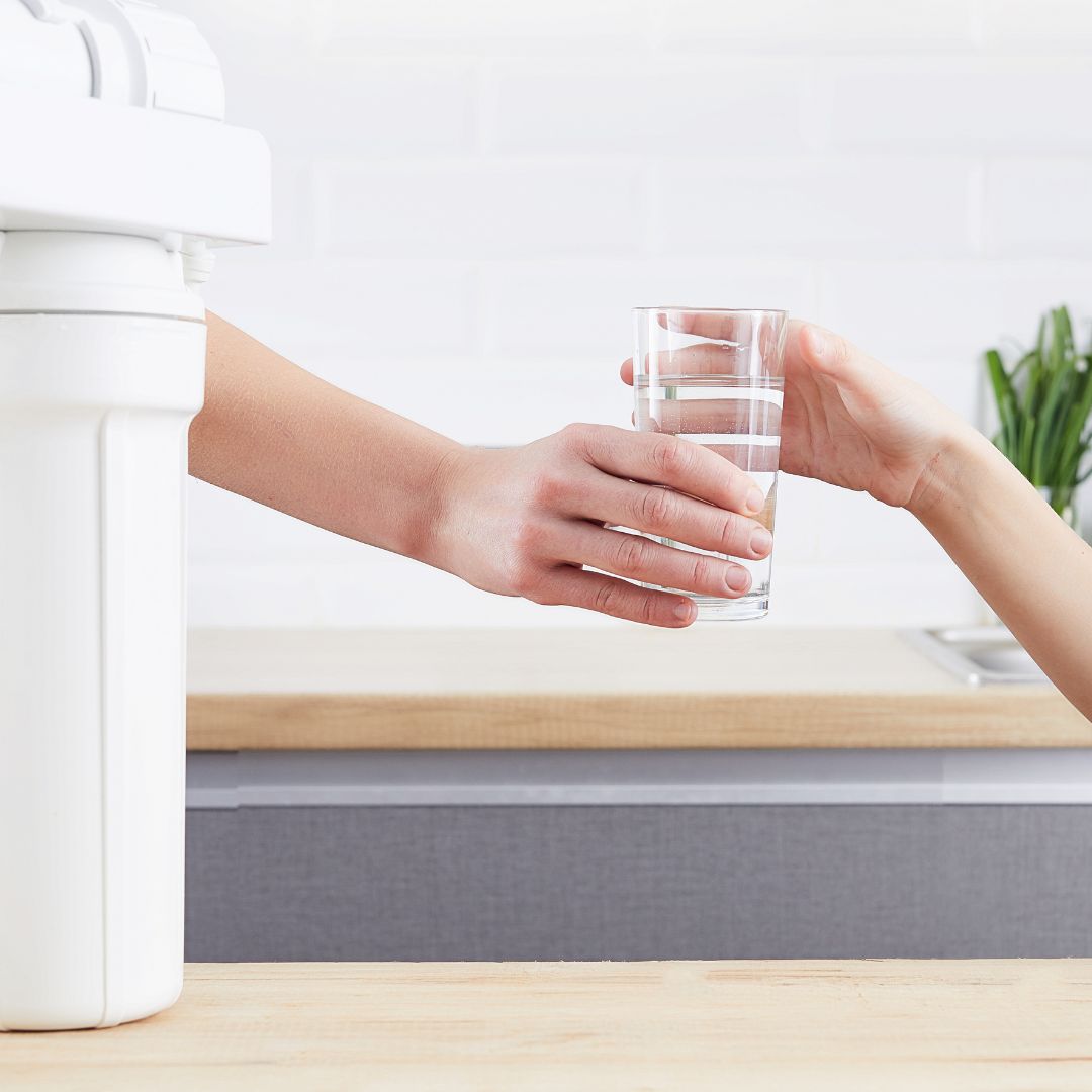 person handing clear glass of water to another person