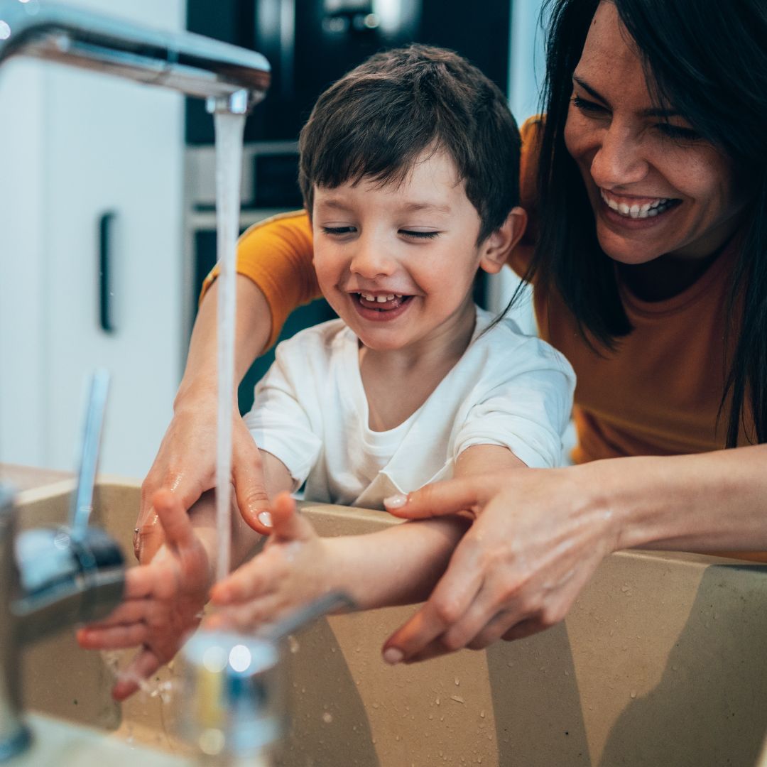 mom helping her young son wash his hands