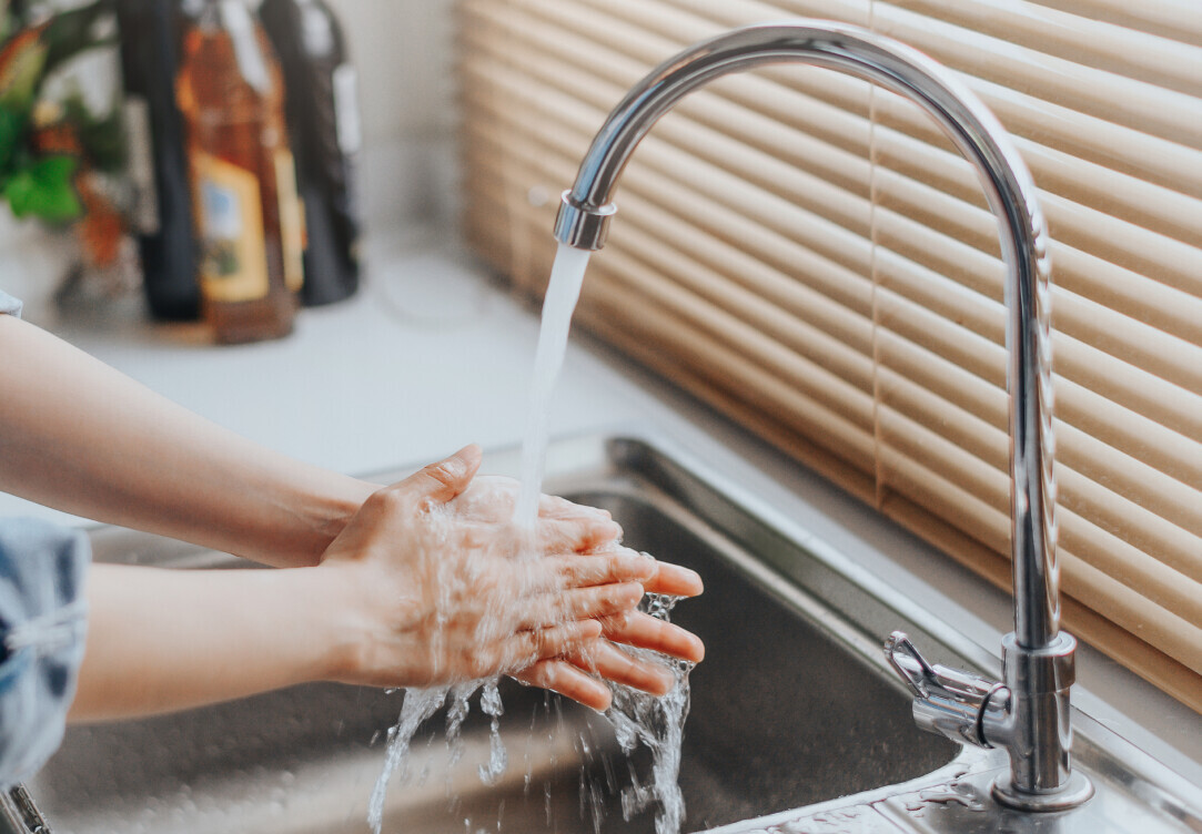 lady washing her hands under a kitchen sink