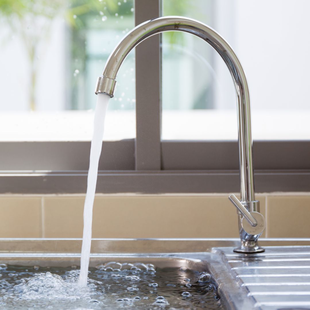 A faucet running water into a sink basin