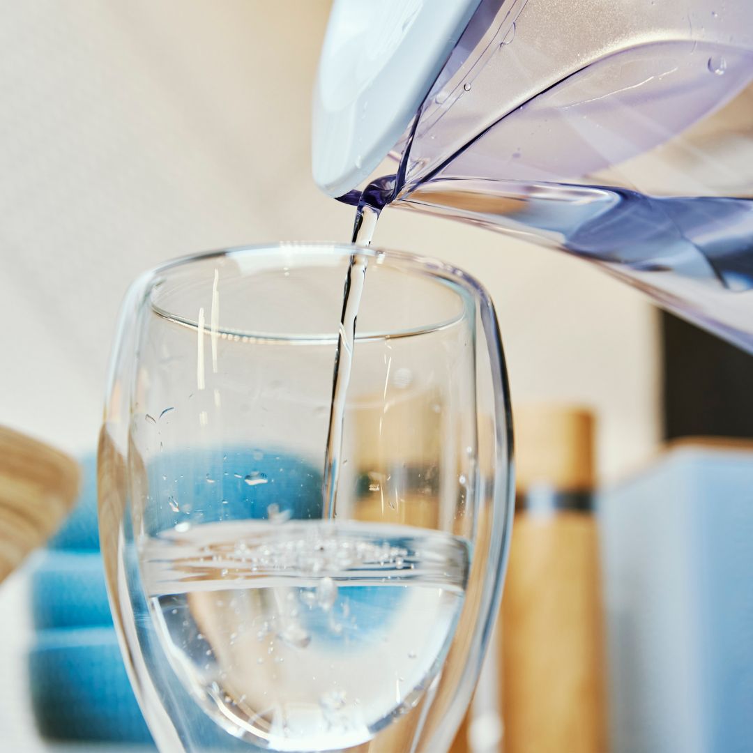 Closeup of someone filling a glass from a filtered pitcher